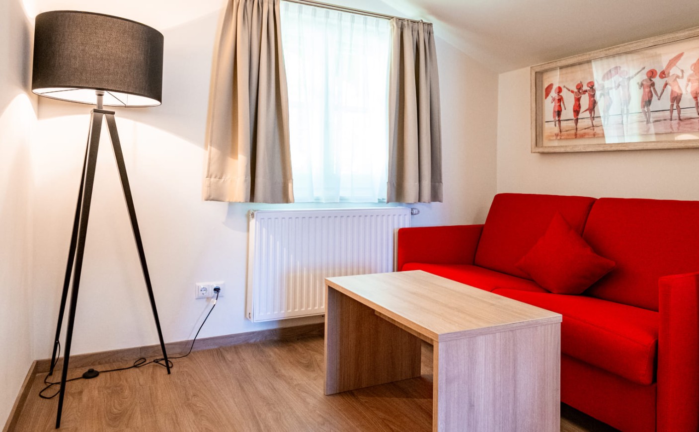 Sitzecke mit rotem Sofa und Designleuchte in der Junior Suite